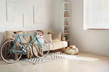 Yastıklı kanepe, ekose, raf ünitesi ve bisiklet oturma odasındaki beyaz duvarın yanında.