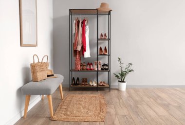 Raflarda şık kıyafetler ve beyaz duvarın yanında farklı kadın ayakkabıları var.