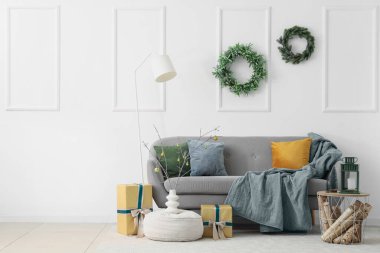 Güzel çelenkler, lamba, kanepe, vazoda dallar, Noel hediyeleri ve odada lamba olan kahve masası.