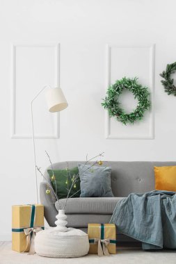 Güzel çelenkler, lamba, kanepe, vazodaki dallar puf üzerinde ve Noel hediyeleri odada.