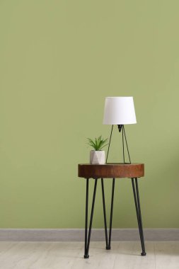Yeşil duvarın yanında kahve masası ve masa lambası.