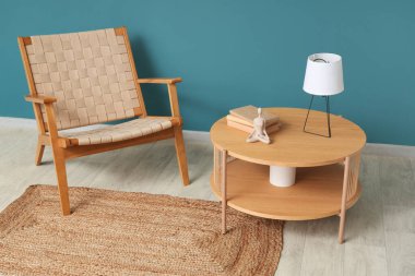 Koltuk ve kahve masası. Masa lambası mavi duvarın yanında.