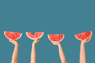 Mavi arka planda tatlı karpuz dilimleri olan kadın elleri