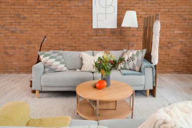 Oturma odasının içinde sonbahar dekoru olan kanepe ve kahve masası.