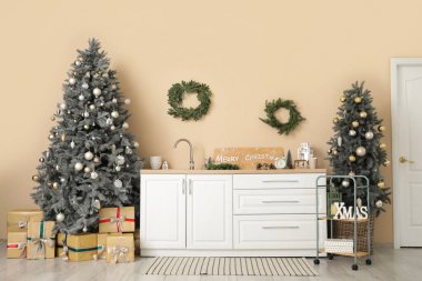 Mutfağın içinde Noel ağaçları, çelenkler ve tezgahlar var.