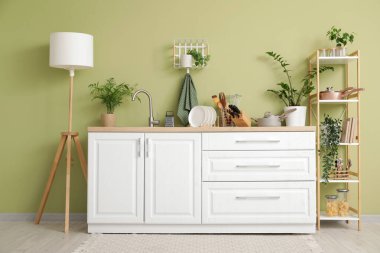 Mutfağın içinde tezgah, raf ünitesi ve mutfak gereçleri var.