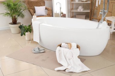 Odada ıslak ayak izleri ve terlikler olan banyo paspası.