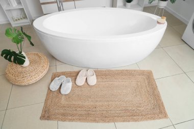 Banyo içinde hasır üzerinde terlikler.