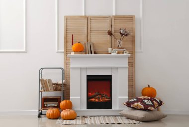 Beyaz şömineli, yastıklı, balkabaklı ve katlanan perdeli bir oturma odası.