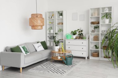 Oturma odasının içinde kanepe, bitki ve bahçe aletleri var.