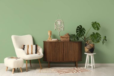 Canavar bitkisi, çekmece sandığı ve yeşil duvarın yanında puf olan koltuk.