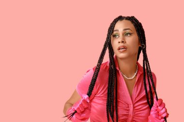 Pembe arka planda örgüleri olan şık Afro-Amerikan kadın.