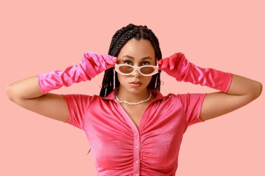 Pembe arka planda örgüleri olan şık Afro-Amerikan kadın.