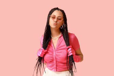 Pembe arka planda örgüleri olan şık Afro-Amerikan kadın.