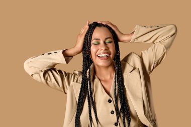 Bej arka planda örgüleri olan şık, Afro-Amerikan bir kadın.