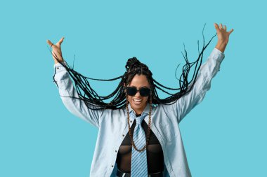 Mavi arka planda örgüleri olan havalı, Afro-Amerikalı bir kadın.