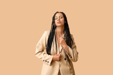 Bej arka planda örgüleri olan şık, Afro-Amerikan bir kadın.