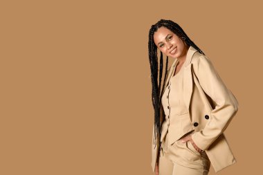 Bej arka planda örgüleri olan şık, Afro-Amerikan bir kadın.