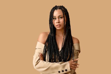 Bej arka planda örgüleri olan şık, Afro-Amerikan bir kadın.