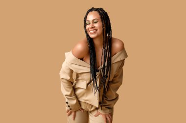 Bej arka planda örgüleri olan şık, Afro-Amerikan bir kadın.