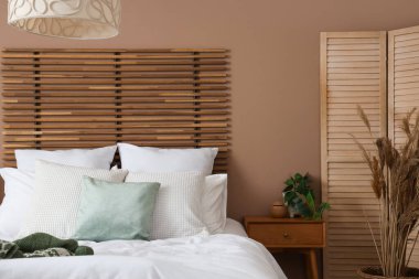 Yatak odasının iç tarafında yastıklı ve komodinli bir yatak.