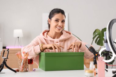 Makyaj ürünleri kutusuyla evde video kaydeden kadın güzellik blogcusu