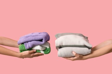 Pembe arka planda farklı giysi yığınları olan kadın elleri