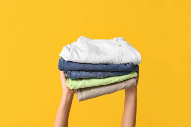 Sarı arka planda farklı kot pantolonları olan kadın elleri.