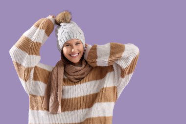 Leylak arka planında kalın giyinmiş genç bir kadın.