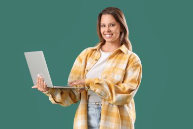 Yeşil arka planda modern laptop kullanan genç bir kadın.
