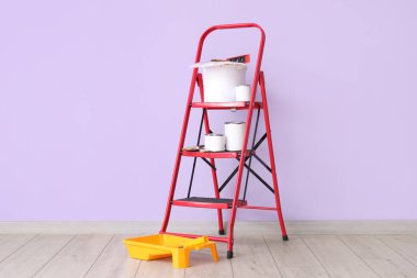 Boya kutularıyla merdiven ve leylak duvarın yanında fırçalar.