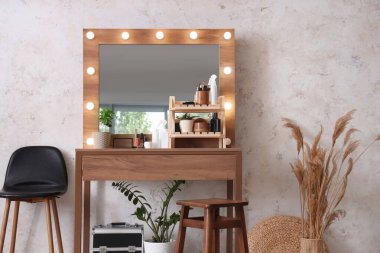 Parlayan aynalı, masalı ve otlu makyaj odasının içi.