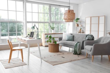 Programcının çalışma yeri, kanepesi ve koltuğu olan aydınlık oturma odasının içinde.