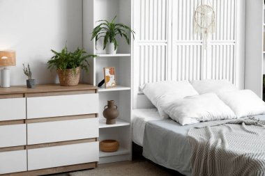 Konforlu yatak, raf üniteleri ve yatak odasının içindeki çekmeceler.