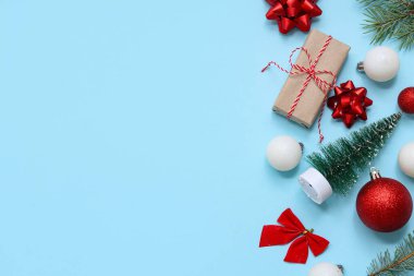 Beautiful composition with Christmas balls, gift box and fir branches on blue background