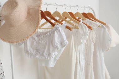 Şık kadın kıyafetleri ve açık renk duvarın yanında şapka.