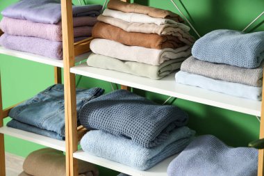 Renk duvarının yanında farklı katlanmış kıyafetleri olan raf ünitesi, yakın plan.