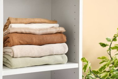 Beyaz rafta katlanmış kıyafet yığını, yakın plan.