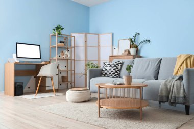 Yumuşak kanepe, sehpa ve oturma odasının içinde bilgisayar olan iş yeri.