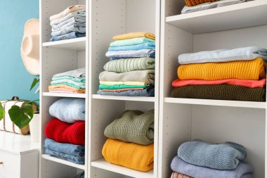 Soyunma odasındaki raflarda şık kıyafetler. Yakın çekim.