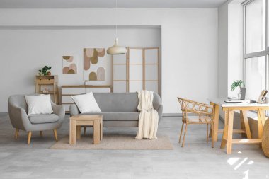 Çalışma yeri, kanepesi ve koltuğu olan aydınlık oturma odasının içinde.