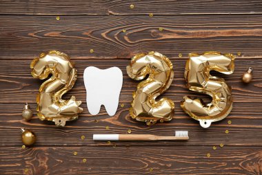 Tahta arka planda kağıt diş, fırça ve Noel topları ile 2025
