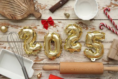 Şekil 2025, mutfak aletleri ve hafif ahşap arka planda Noel topları.