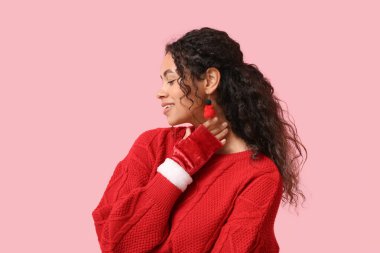 Pembe arka planda neşeli küpeler takan güzel Afro-Amerikalı bir kadın. Noel kutlaması