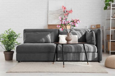 Oturma odasındaki masanın üstünde manolya çiçekleri olan vazo.