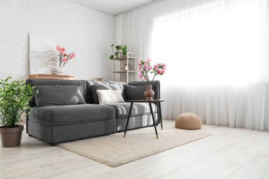 Kanepe ve vazolarda manolya çiçekleri olan oturma odasının içinde.