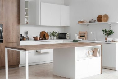 Masası, tezgahı ve dolabı olan modern mutfağın içi.