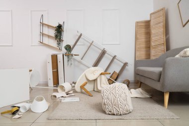 Depremden sonra mobilyaların devrildiği dağınık bir oturma odası.