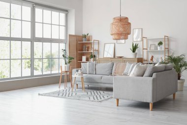 Interior of light living room with grey sofas, shelf units and plants clipart