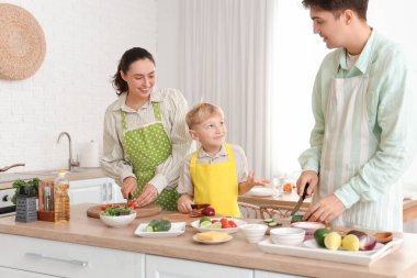 Küçük çocuk ve ailesi mutfakta Fajita için sebze kesiyor.